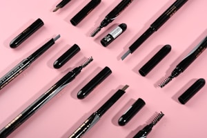 Assortment of makeup brushes and tools laid out on a soft pink background