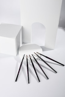 Variety of eyebrow pencils and gels arranged on a green-toned surface