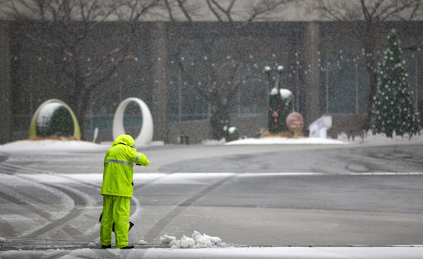 A professional ShovelGigs team member clearing snow with vibrant green tools against a sleek black background.