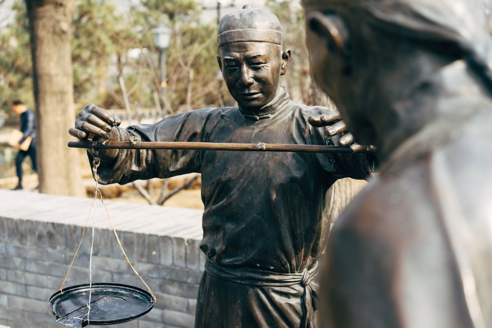 homem no colete de couro preto segurando a estátua do rifle