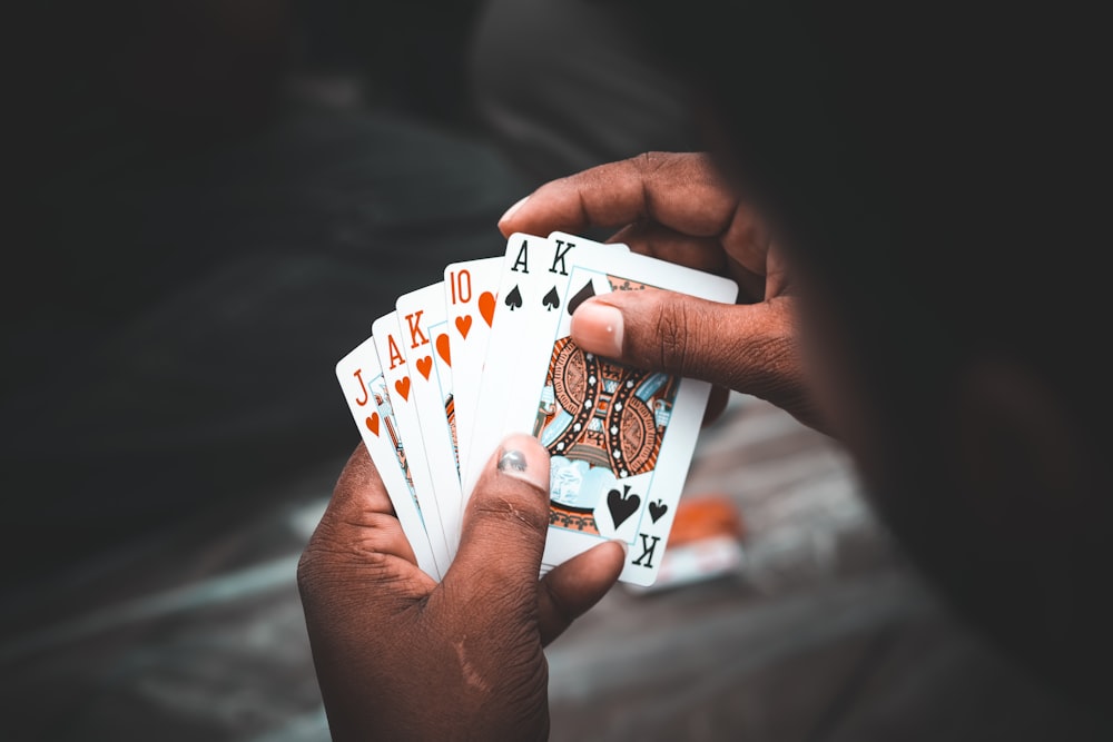 person holding 10 of diamonds and 10 of diamonds playing cards