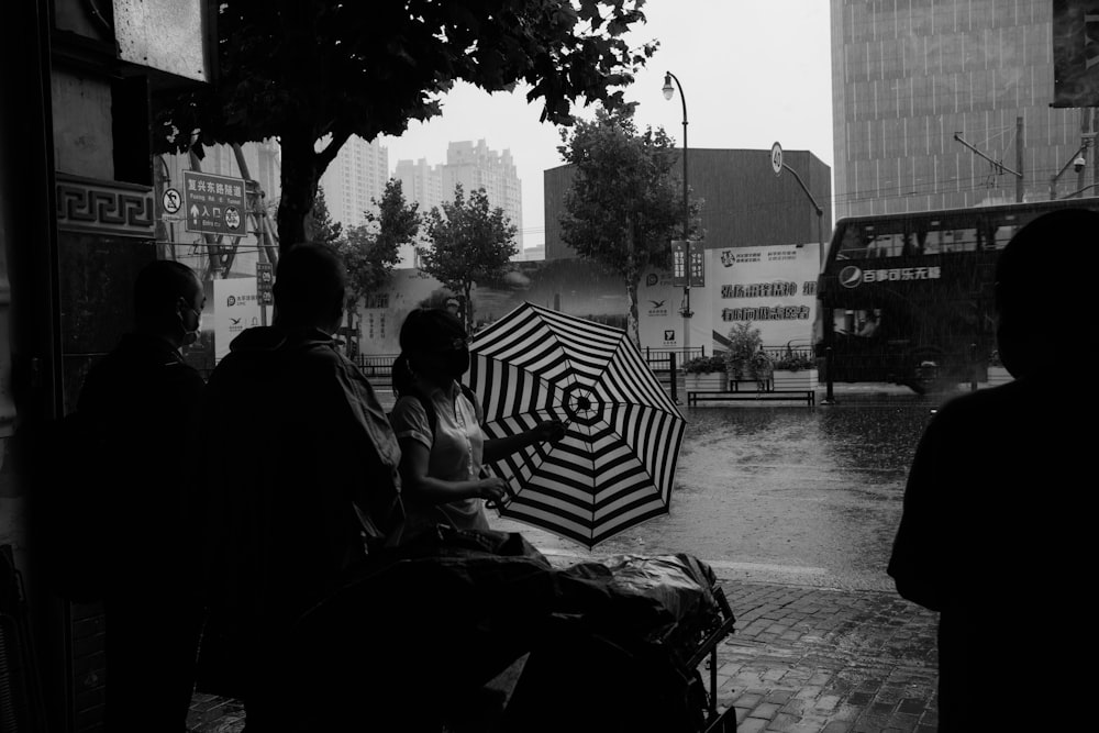 grayscale photo of man sitting on chair near umbrella
