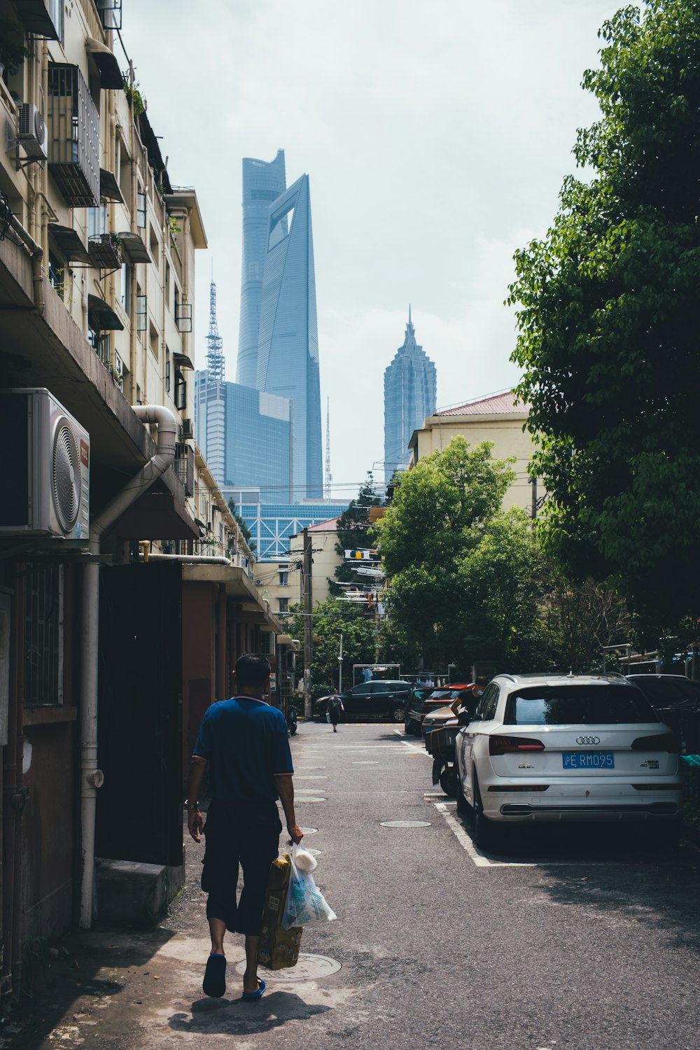 man in blue t-shirt walking on sidewalk during daytime