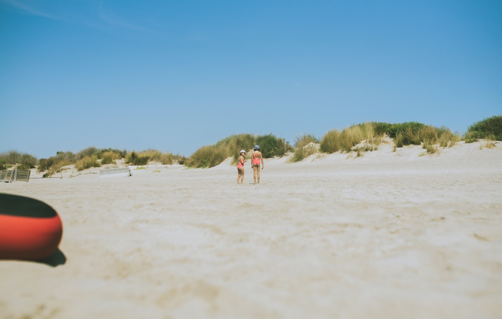 2 people walking on white sand beach during daytime