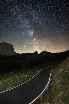 gray concrete road between green grass field during night time