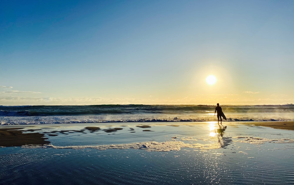 person walking on beach during sunset