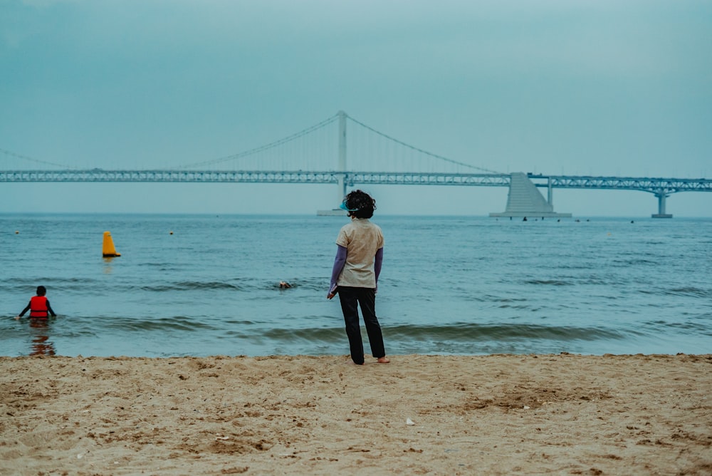 woman in black pants standing on beach during daytime