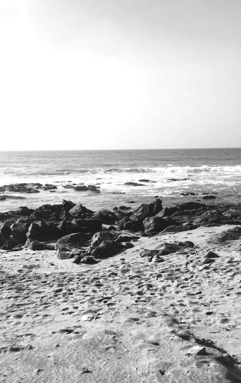 grayscale photo of sea waves crashing on rocks