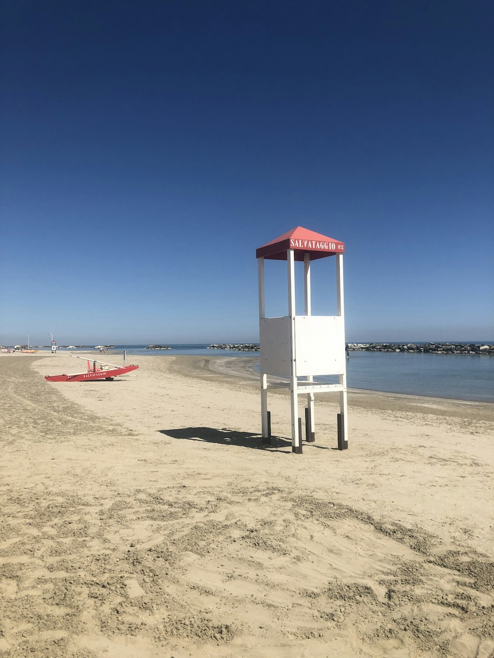日中のビーチショアにある白と赤のライフガードタワー