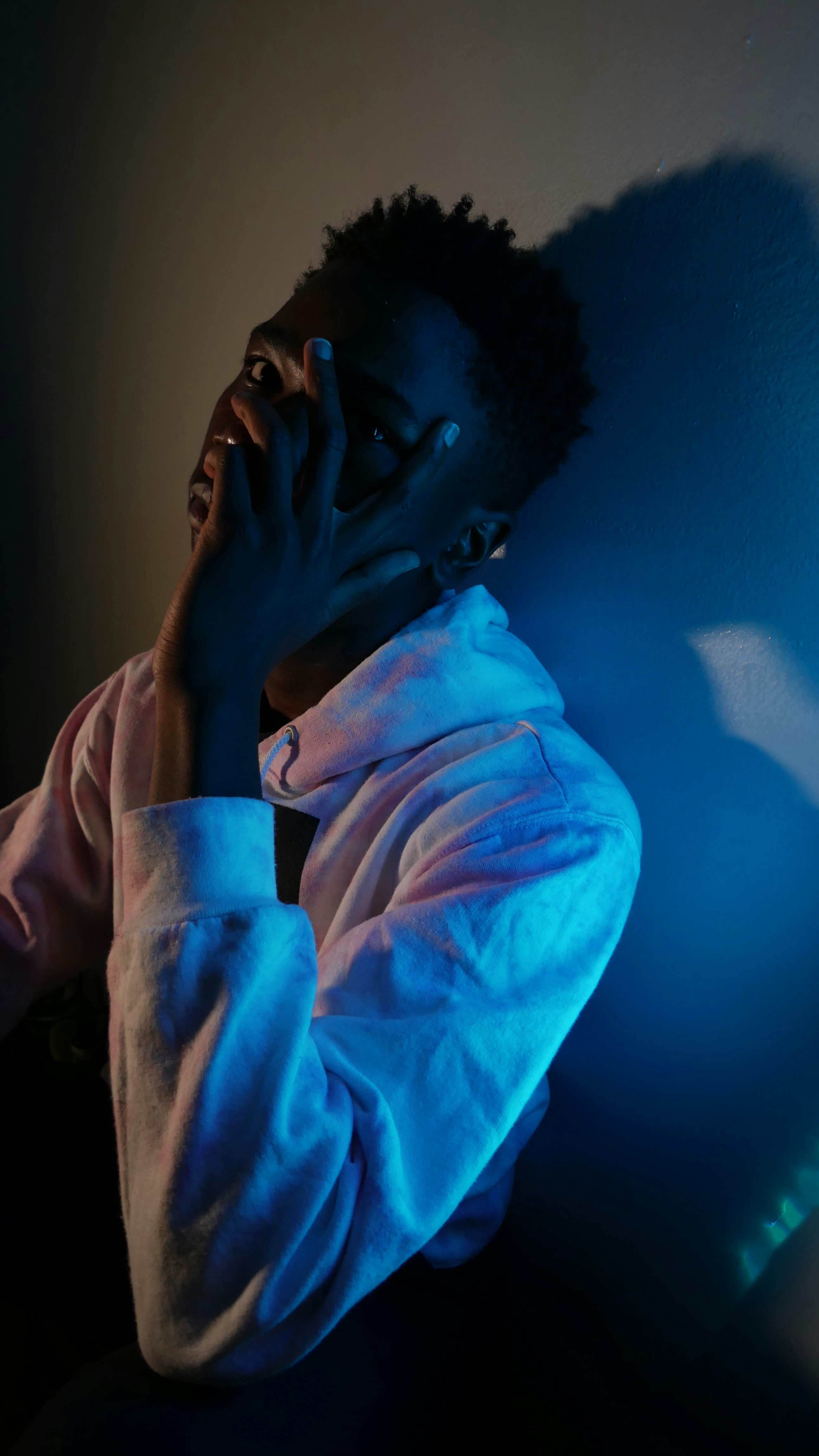 man in gray hoodie covering his face with his hand