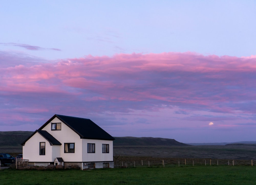 white and black house on green grass field under orange and blue sky