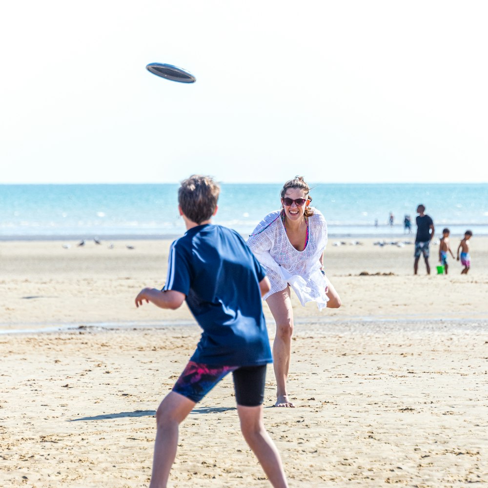 Junge im blau-weißen Hemd läuft tagsüber am Strand