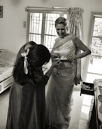 A friendly support worker assisting a person with dressing in a bright, welcoming home.