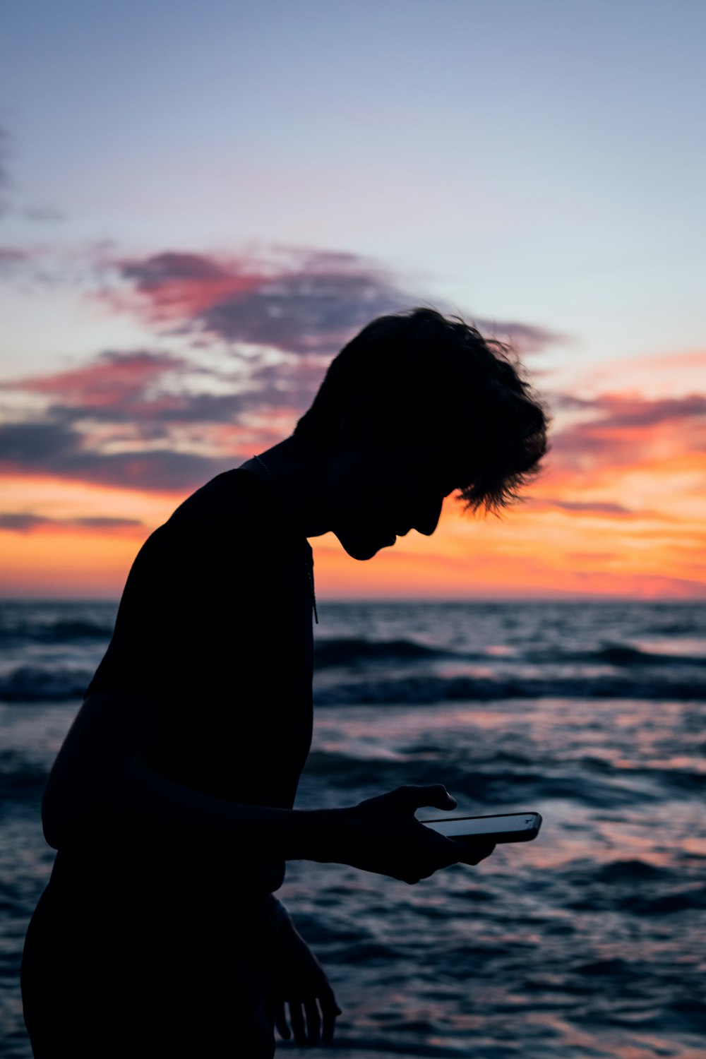 silhouette of man sitting on beach during sunset