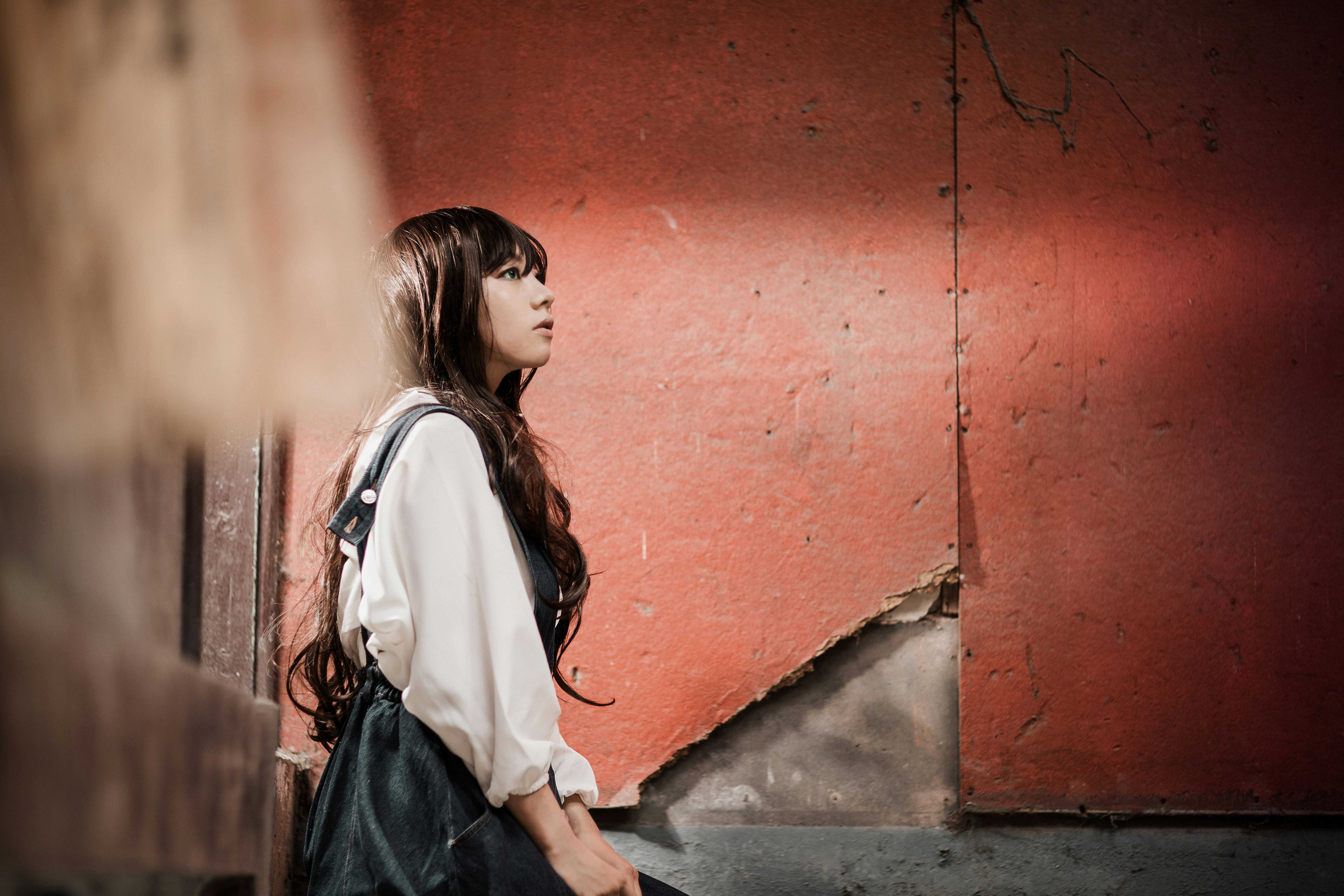 woman in white shirt and black skirt sitting on concrete wall