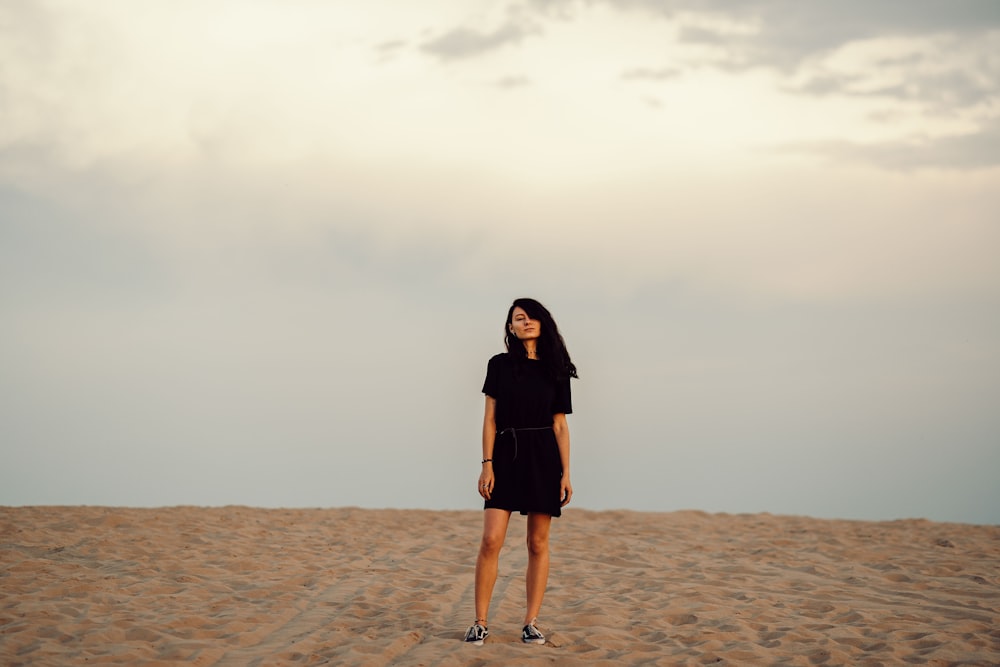 woman in black dress standing on brown sand during daytime