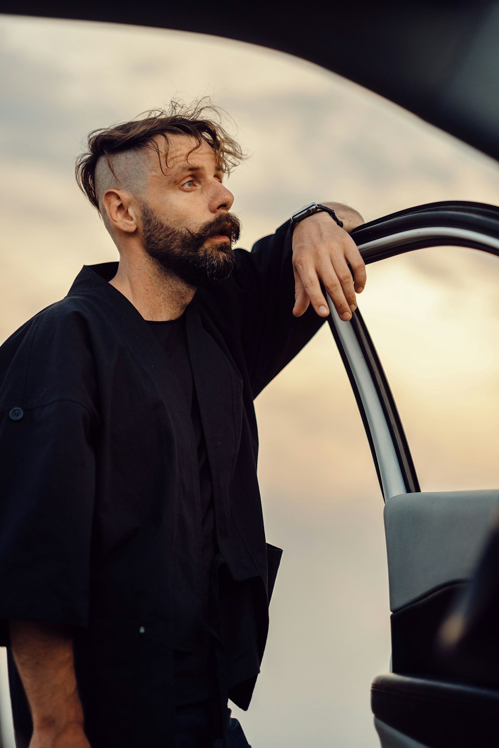 man in black long sleeve shirt standing beside car during daytime