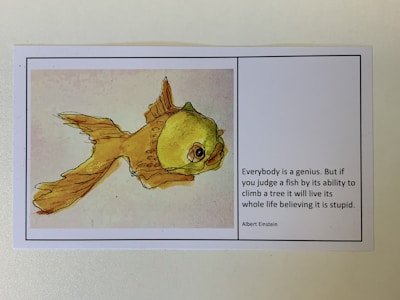 An illustration of a goldfish on the left side, accompanied by a quote from Albert Einstein on the right. The quote discusses the idea of judging individuals based on irrelevant criteria.
