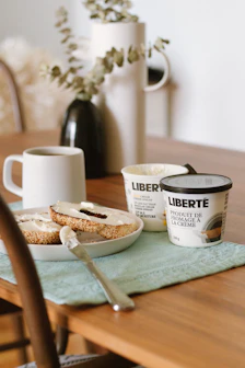 white and black ceramic mug beside brown bread on blue table