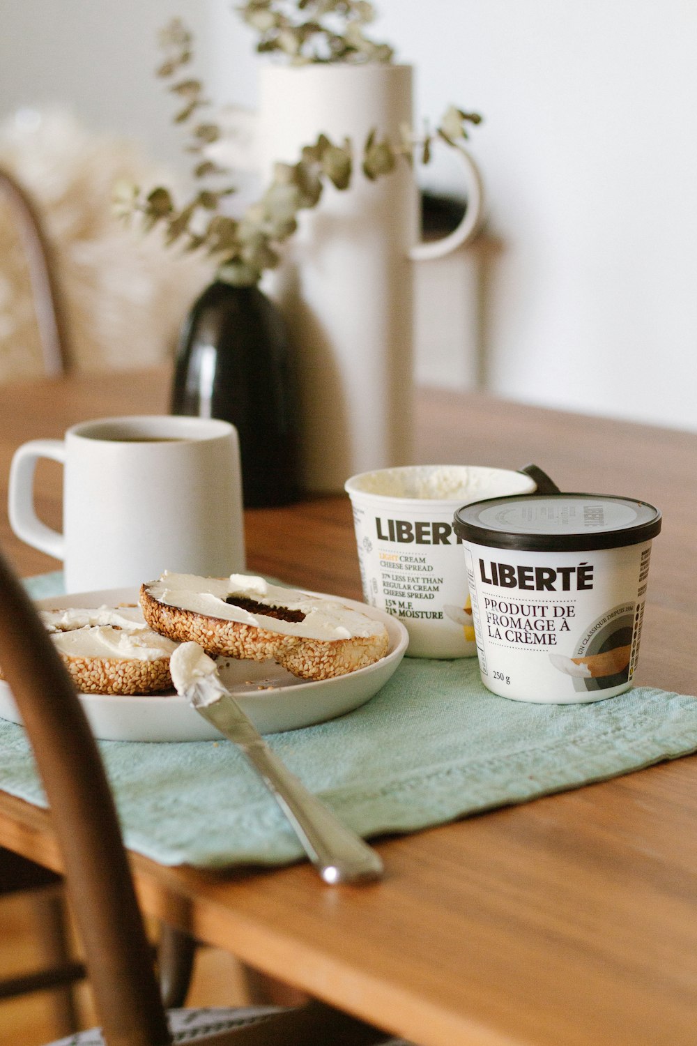 white and black ceramic mug beside brown bread on blue table