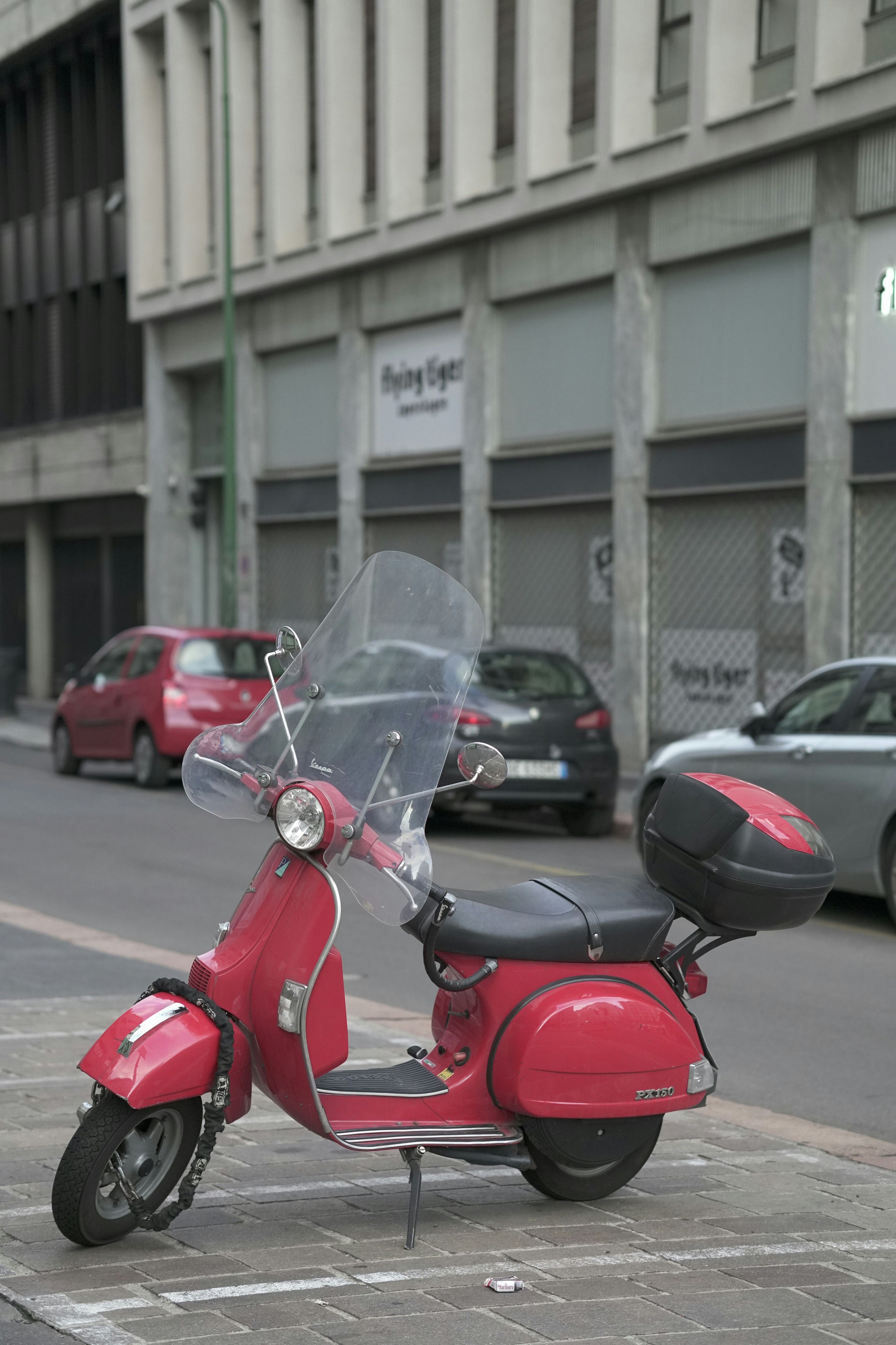 red motor scooter parked on the side of the road during daytime