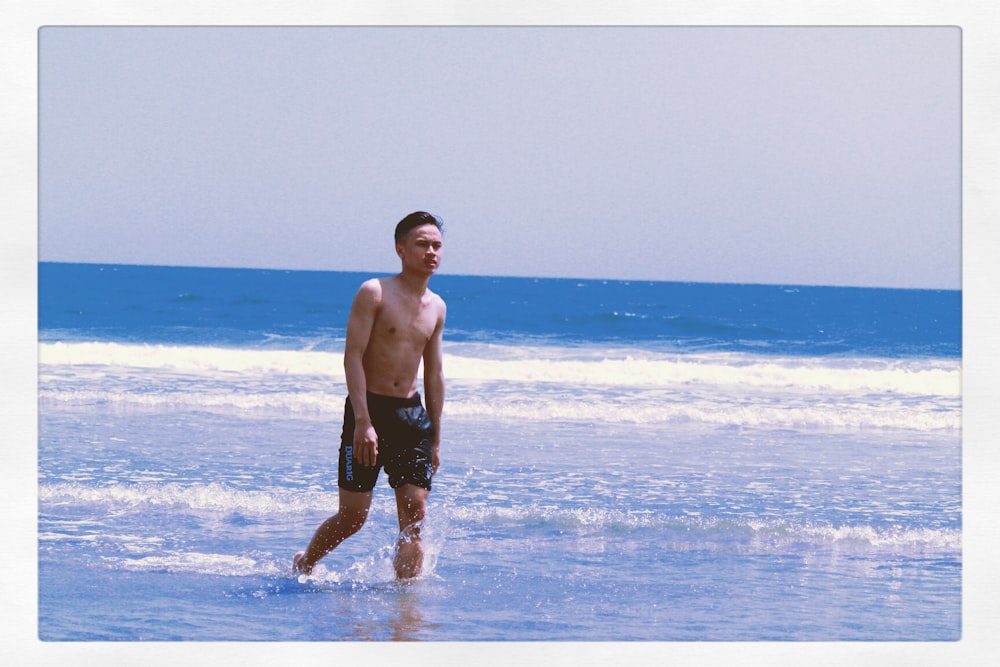 man in black shorts standing on beach during daytime