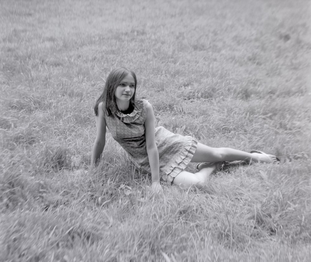 woman in gray sleeveless dress sitting on grass field during daytime