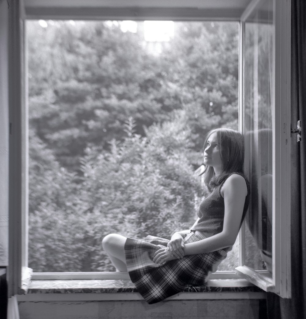woman in plaid dress sitting on window