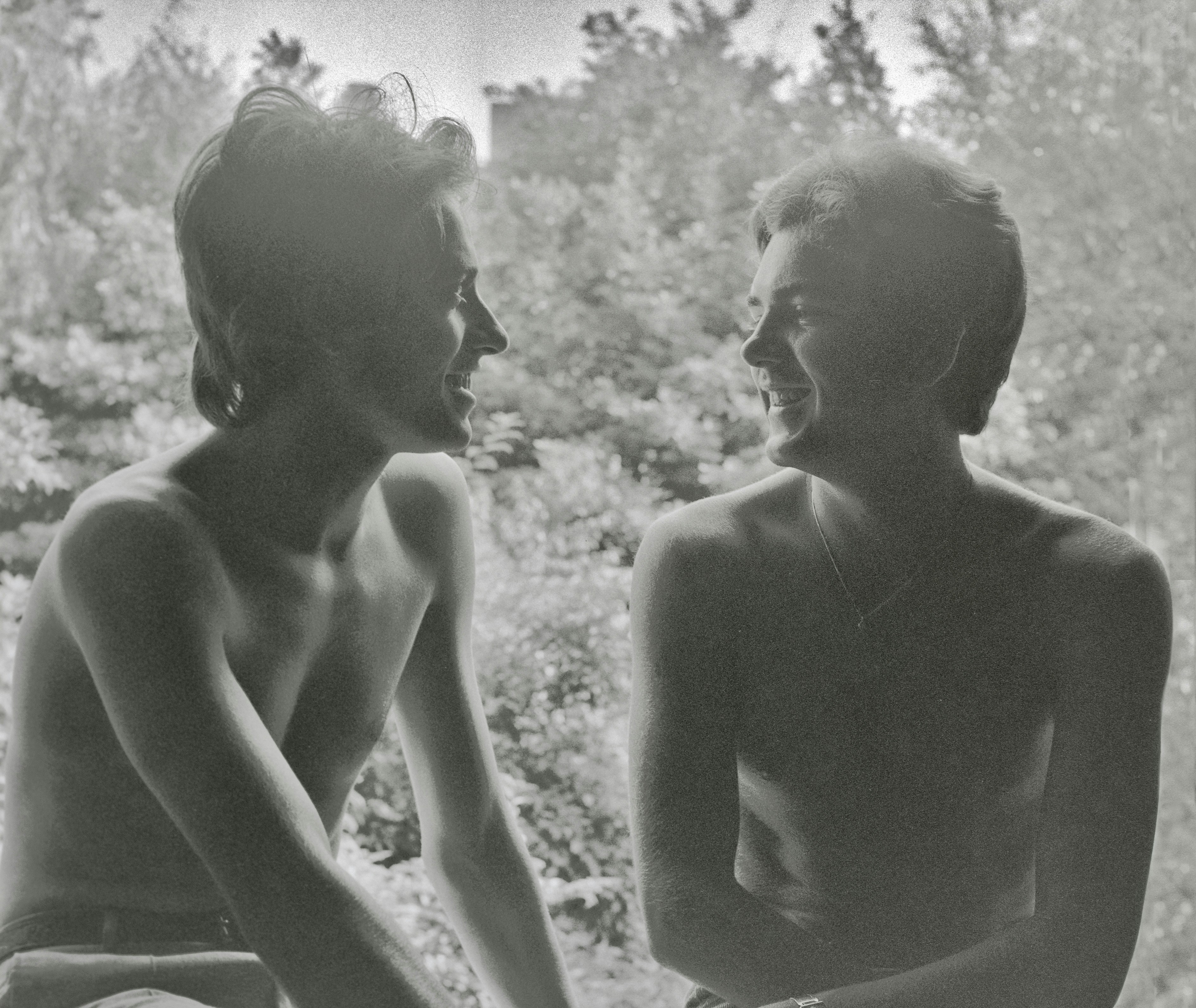 2 topless women standing near trees during daytime