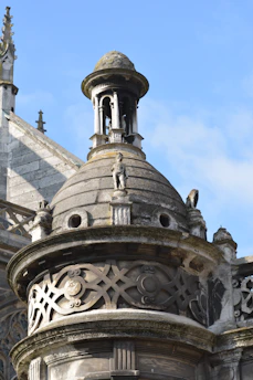 A detailed custom cupola perched atop a classic home roof under a clear blue sky.