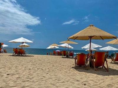 A sunny beach scene with clear blue water and a comfortable lounge chair.