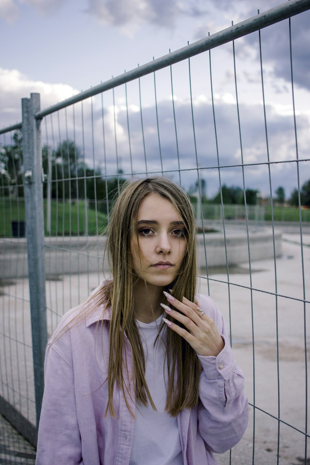 woman in pink long sleeve shirt standing near gray metal fence during daytime