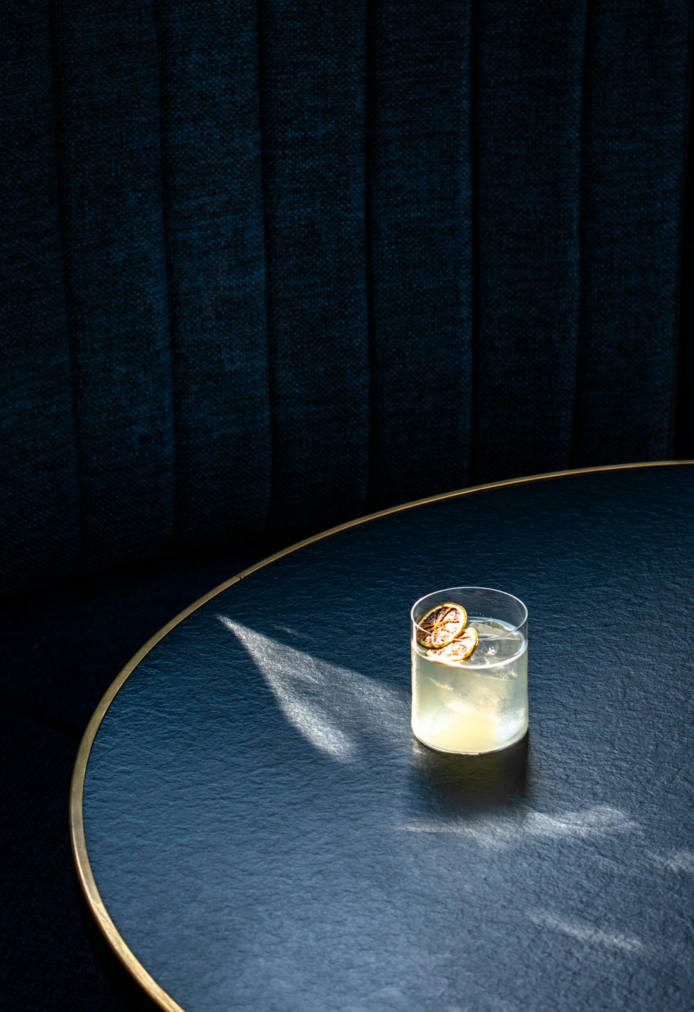 klares Trinkglas mit weißer Flüssigkeit auf blauem runden Tisch