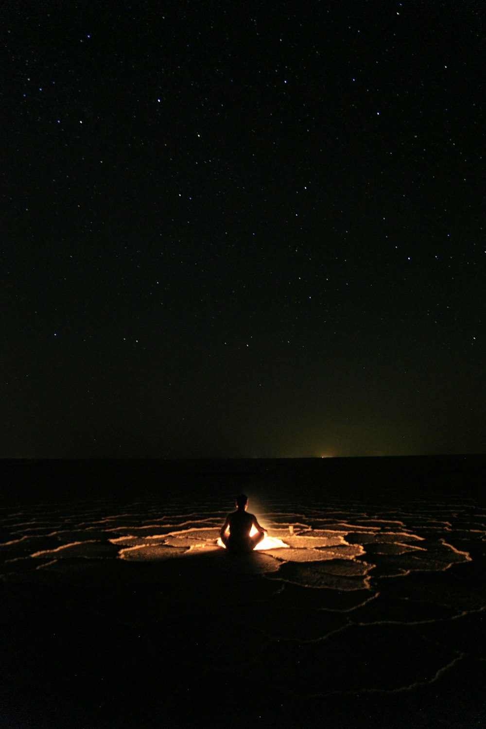 person sitting on sand during night time