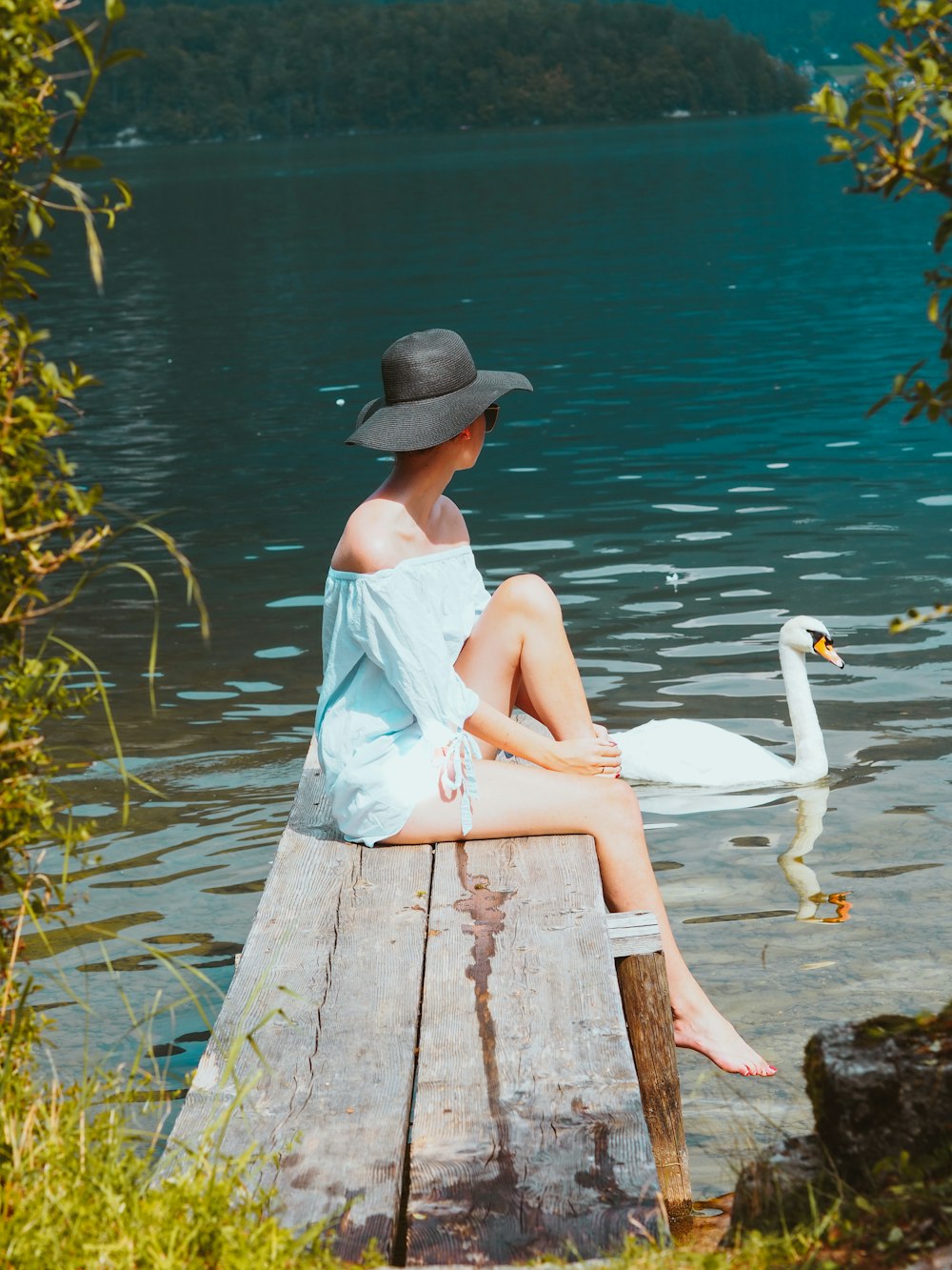 woman in white dress sitting on brown wooden dock during daytime