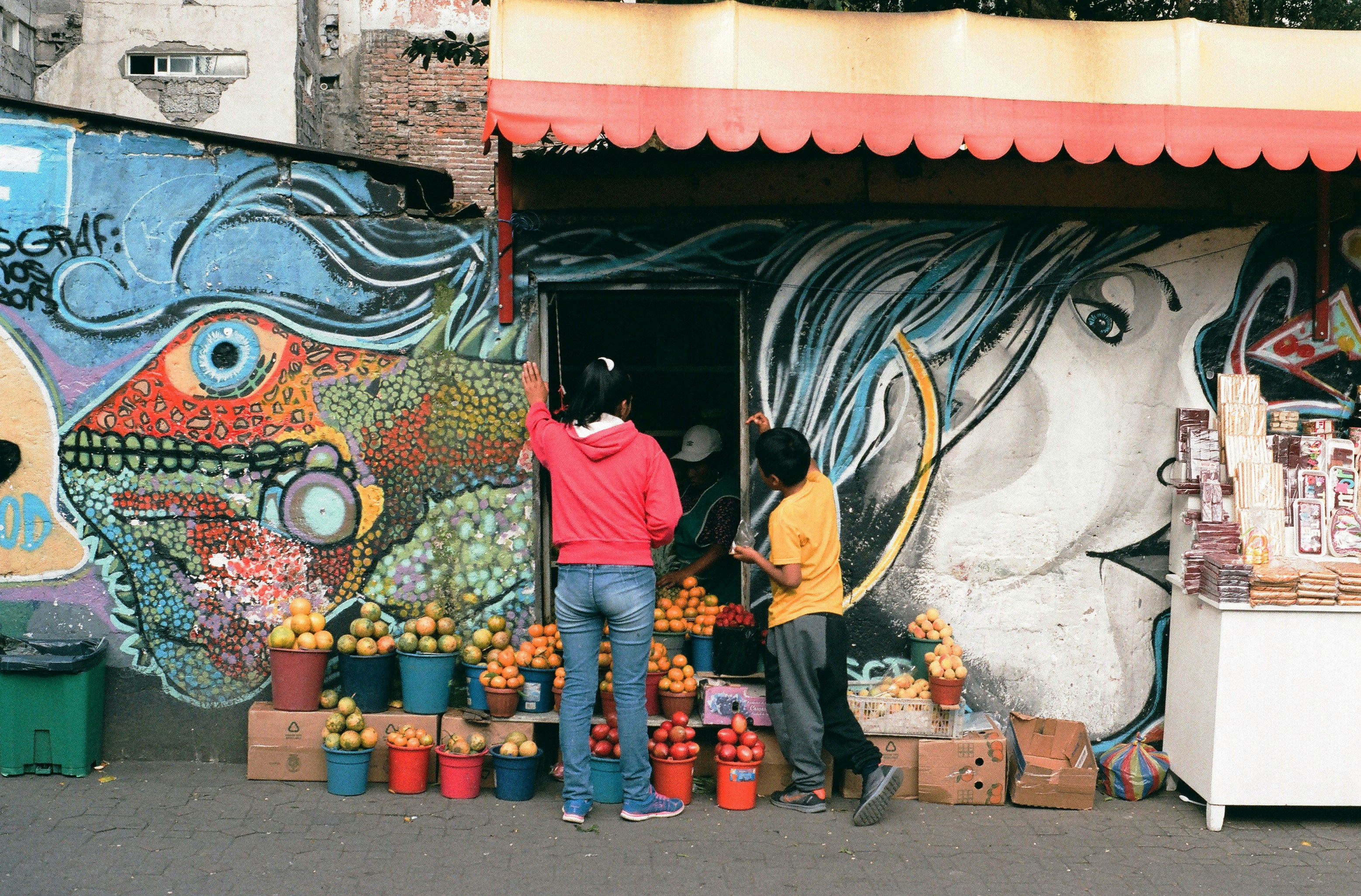 man in black t-shirt and blue denim jeans standing in front of graffiti wall