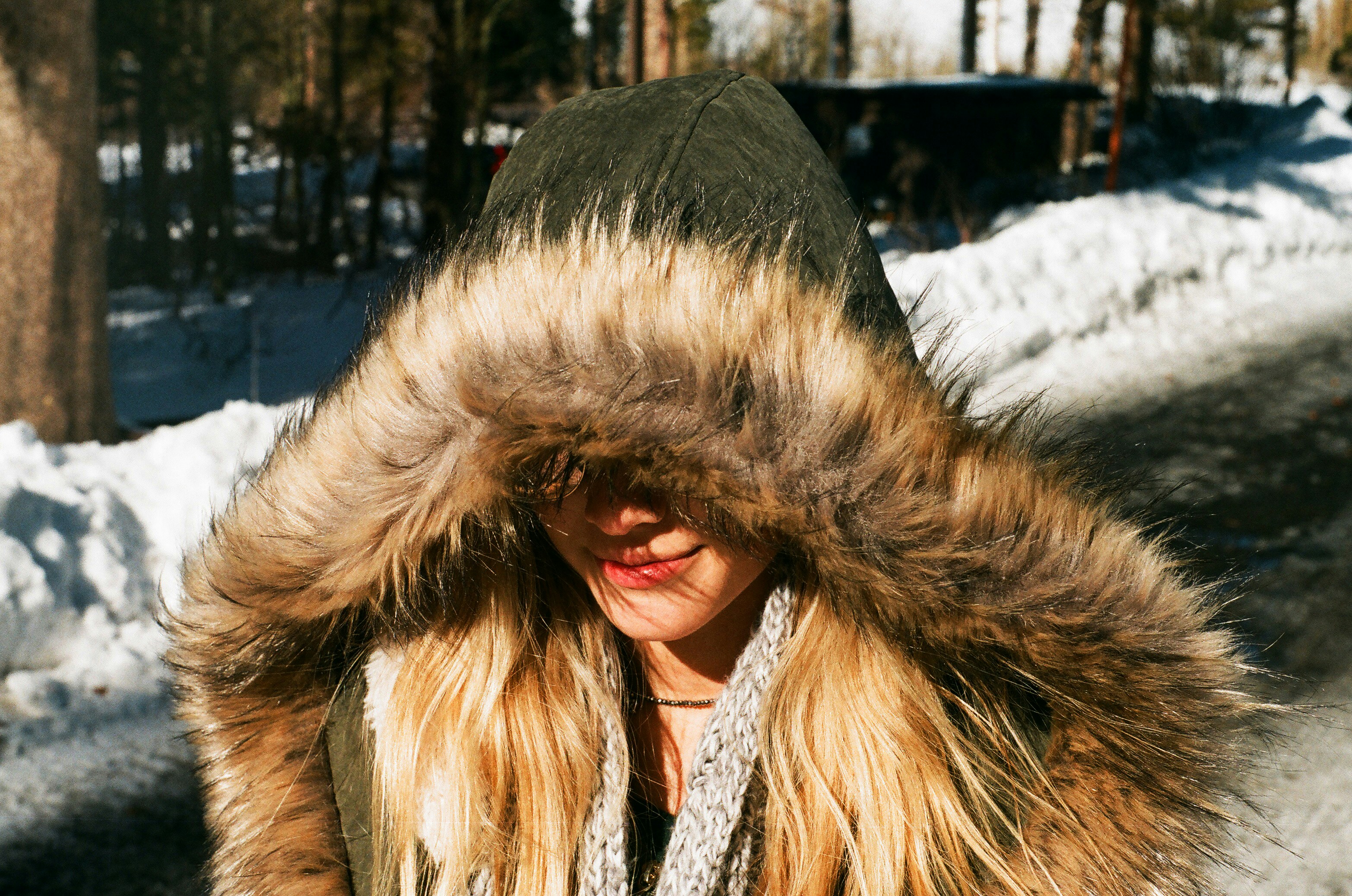 Woman in black and brown fur coat standing on snow covered ground