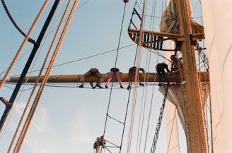 Crew members performing maintenance on a ship's deck under clear blue skies.