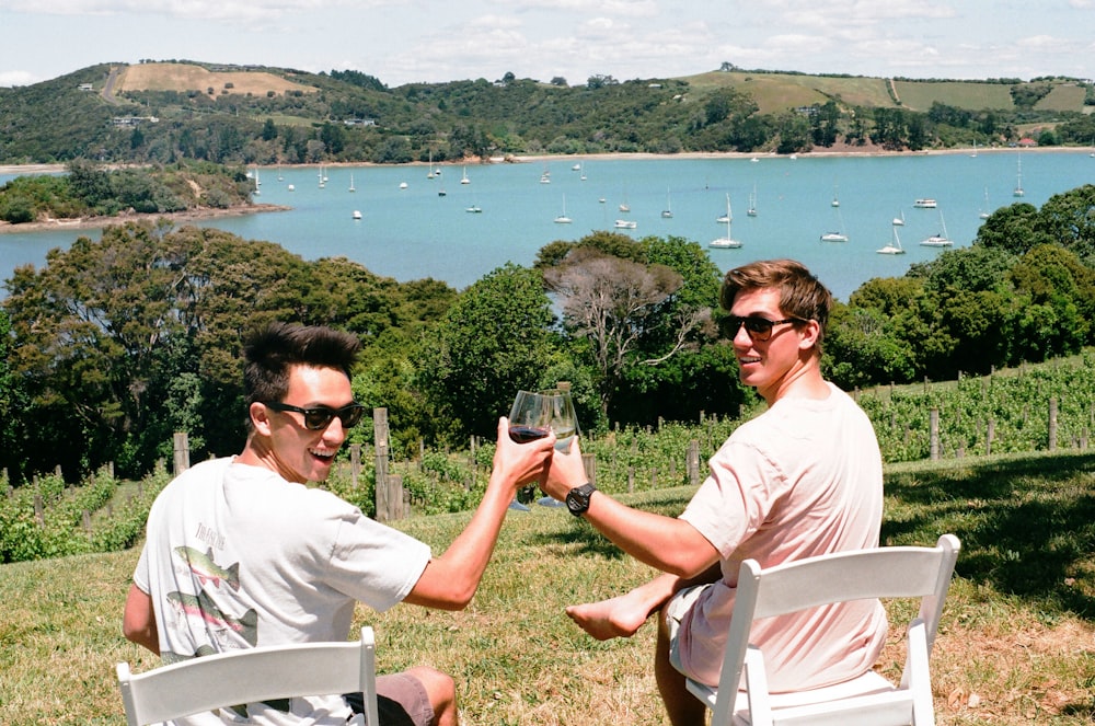 man in white crew neck shirt sitting on white chair holding clear drinking glass