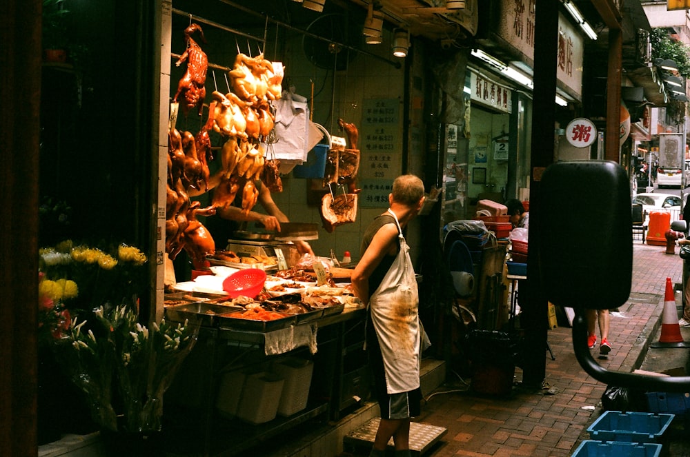 man in white t-shirt standing in front of food stall during nighttime
