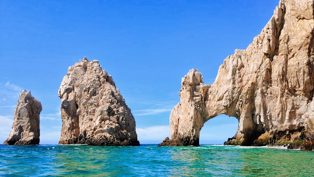 formação rochosa marrom no mar azul sob o céu azul durante o dia