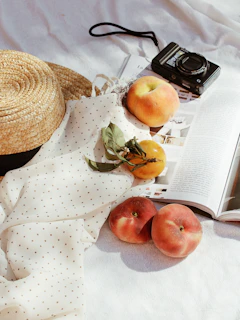 Close-up of a sunhat resting on a wooden table beside a fresh iced latte and a well-loved fashion magazine