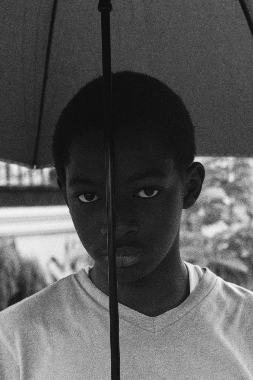 Graustufenfoto eines Jungen im Rundhalsshirt mit Regenschirm