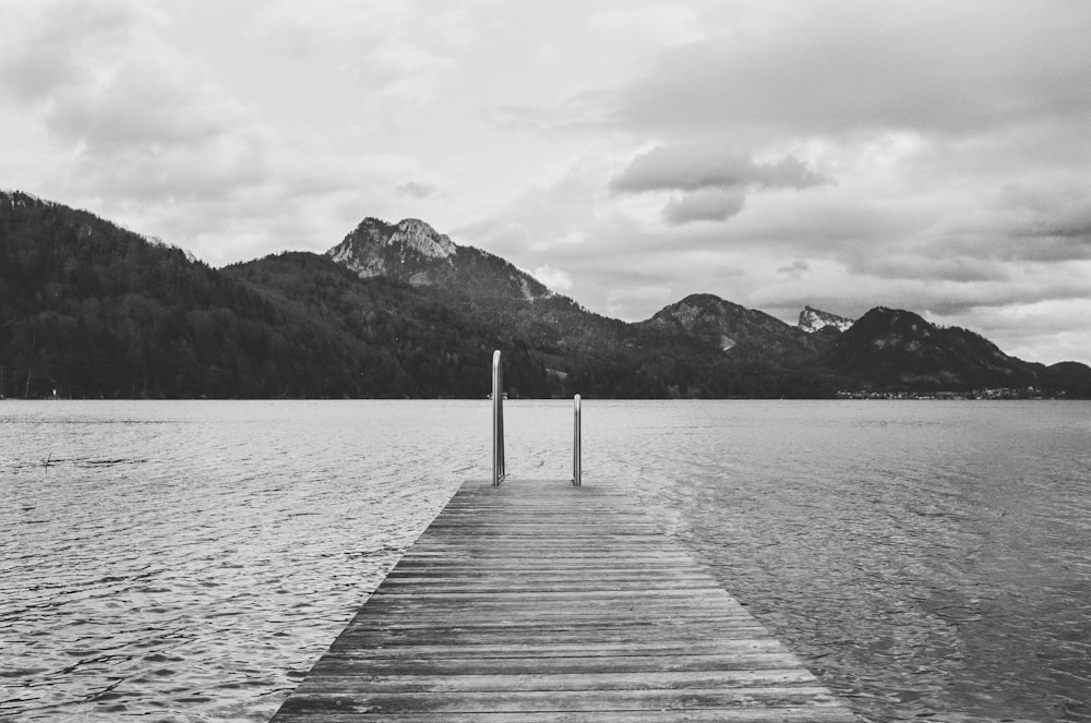 grayscale photo of wooden dock on lake