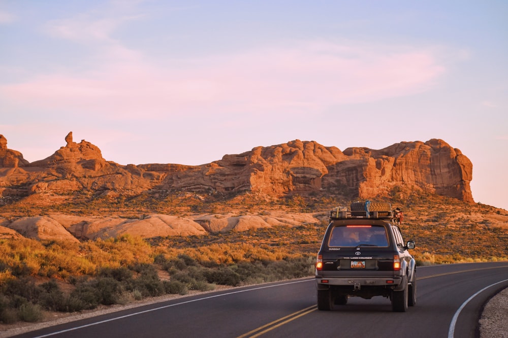 Schwarzer SUV tagsüber auf der Straße in der Nähe des Brown Rock Mountain