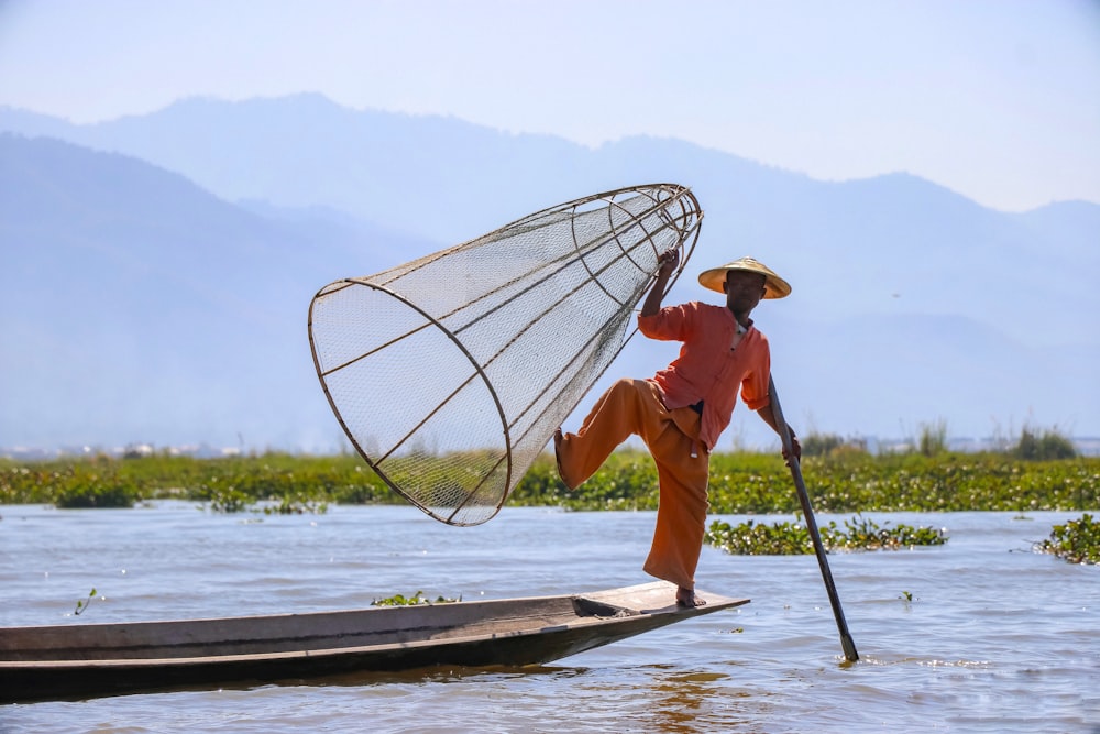 woman in orange shirt and brown hat standing on white boat on sea during daytime