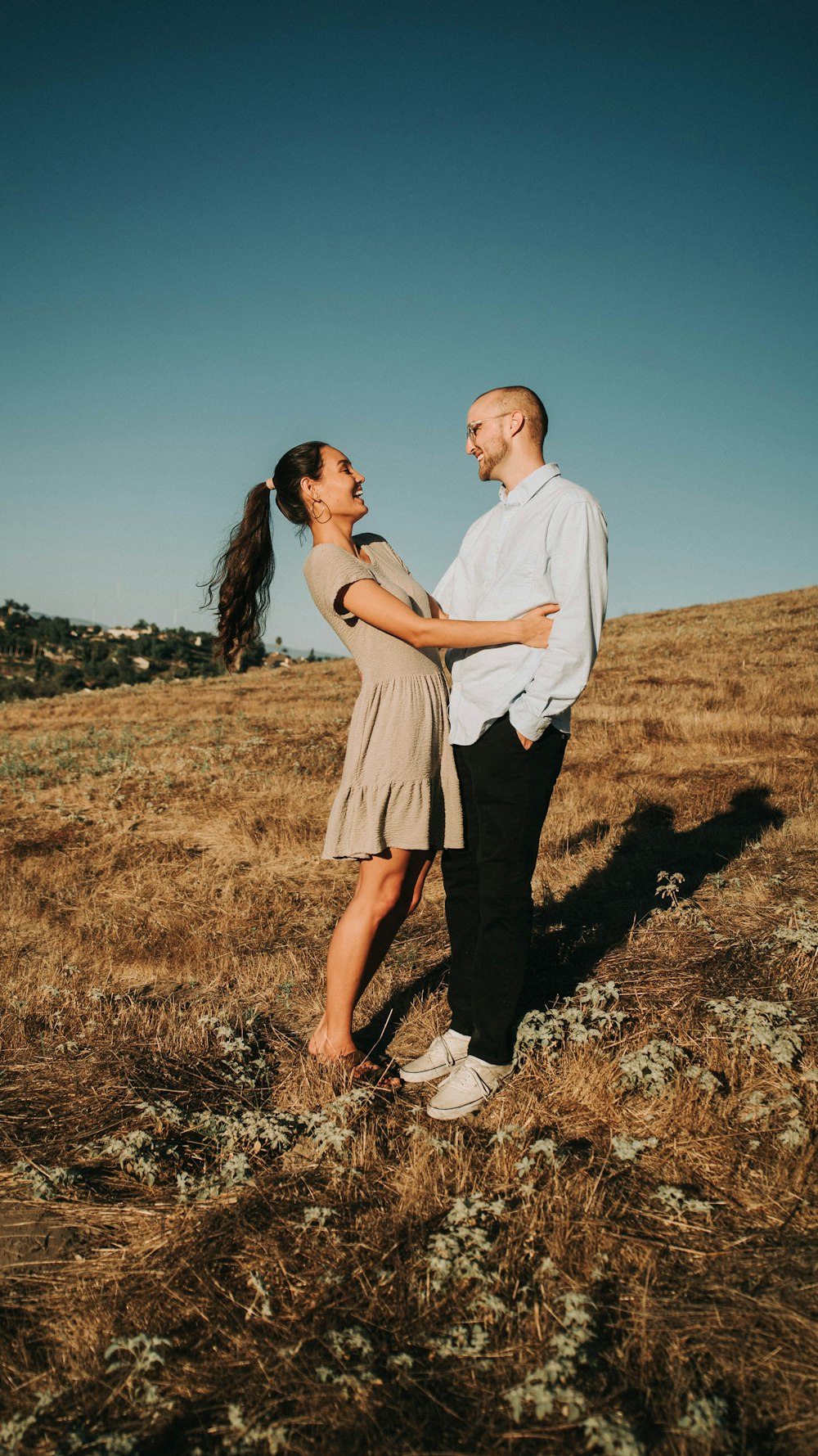 man and woman holding hands while walking on brown grass field during daytime