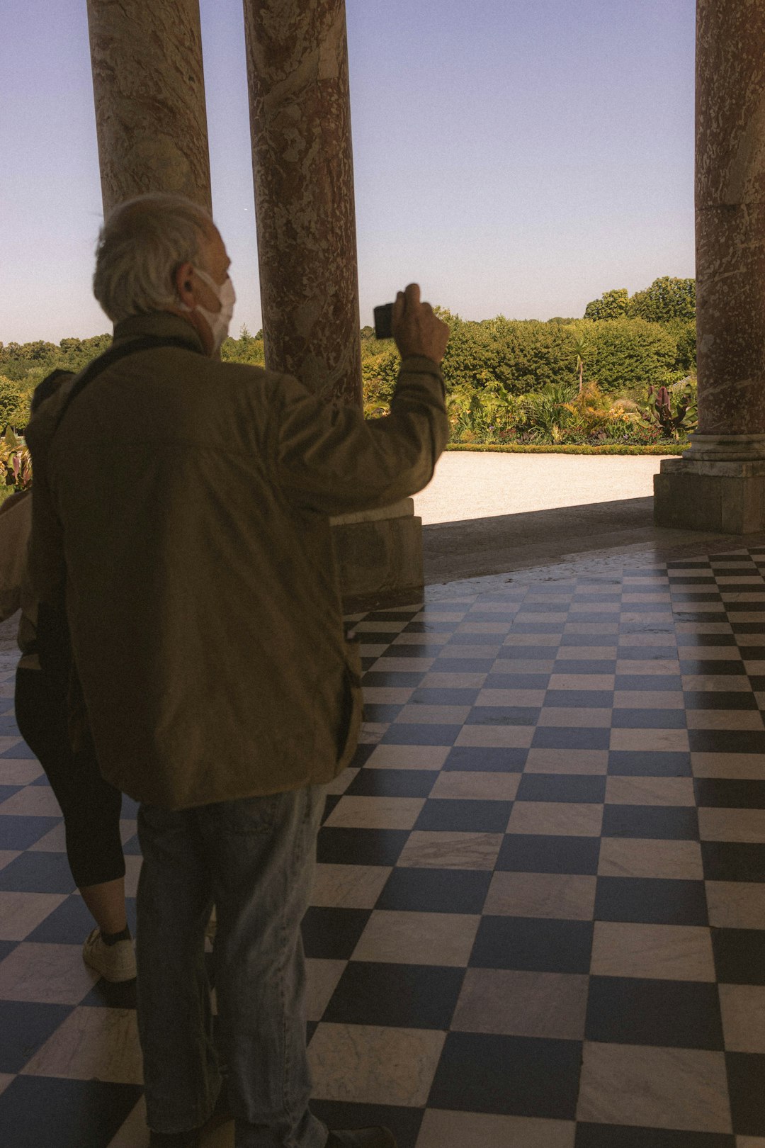 man in green jacket standing on gray and white floor tiles during daytime