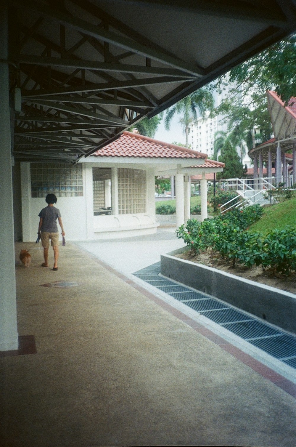 man in white t-shirt and brown shorts walking on sidewalk during daytime