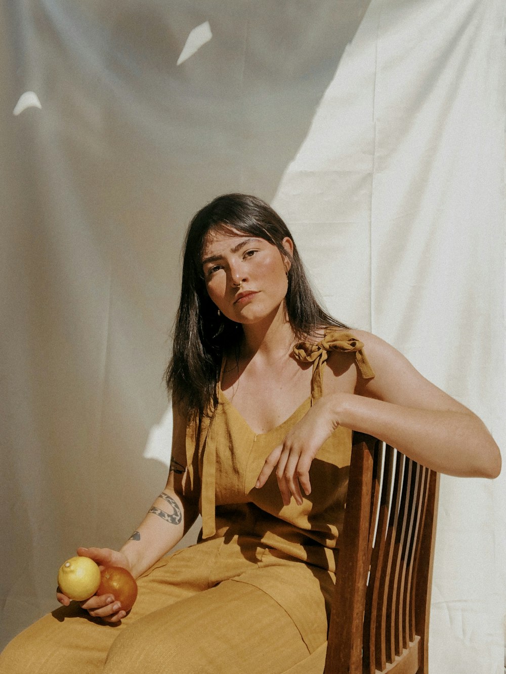 woman in orange sleeveless dress sitting on brown wooden chair